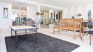 Amplia sala de estar con un gran ventanal, un banco de madera, una mesa de comedor y un sofá.