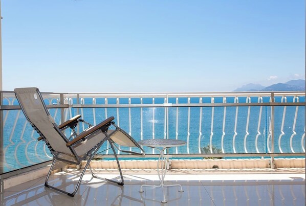 A balcony with a pool view, a lounge chair, and a small table.
