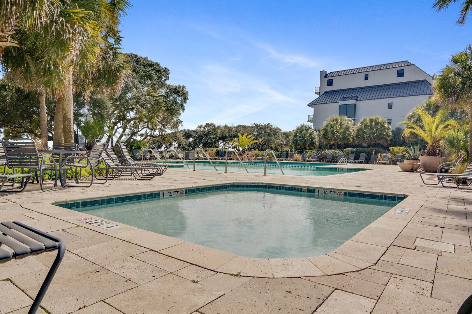 A pool area with multiple swimming pools, lounge chairs, and palm trees.