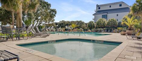 A pool area with multiple swimming pools, lounge chairs, and palm trees.