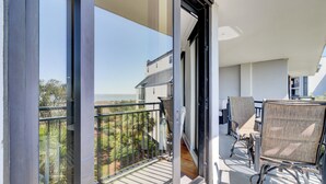 A balcony with a view of a building and trees, furnished with chairs and a table. - 314 C Shipwatch by AvantStay | OCEANFRONT WITH OCEAN VIEW (Isle Of Palms)