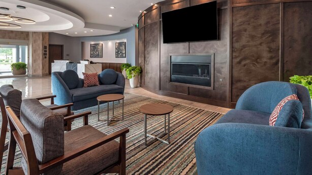 A modern living room with a fireplace, sofas, and a TV mounted on the wall. - Cambria Hotel Nashville Airport (Nashville)