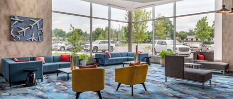 A spacious lobby with a blue sofa, yellow armchairs, and a patterned carpet.