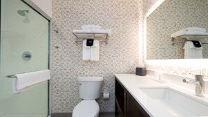 Een moderne badkamer met een douchecabine van glas, een toilet en een wastafel met spiegel erboven.