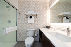 Un baño moderno con cabina de ducha de vidrio, inodoro y lavabo con espejo.