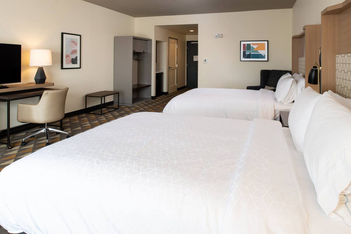 Une chambre d’hôtel avec deux lits, un bureau, une chaise et un téléviseur.