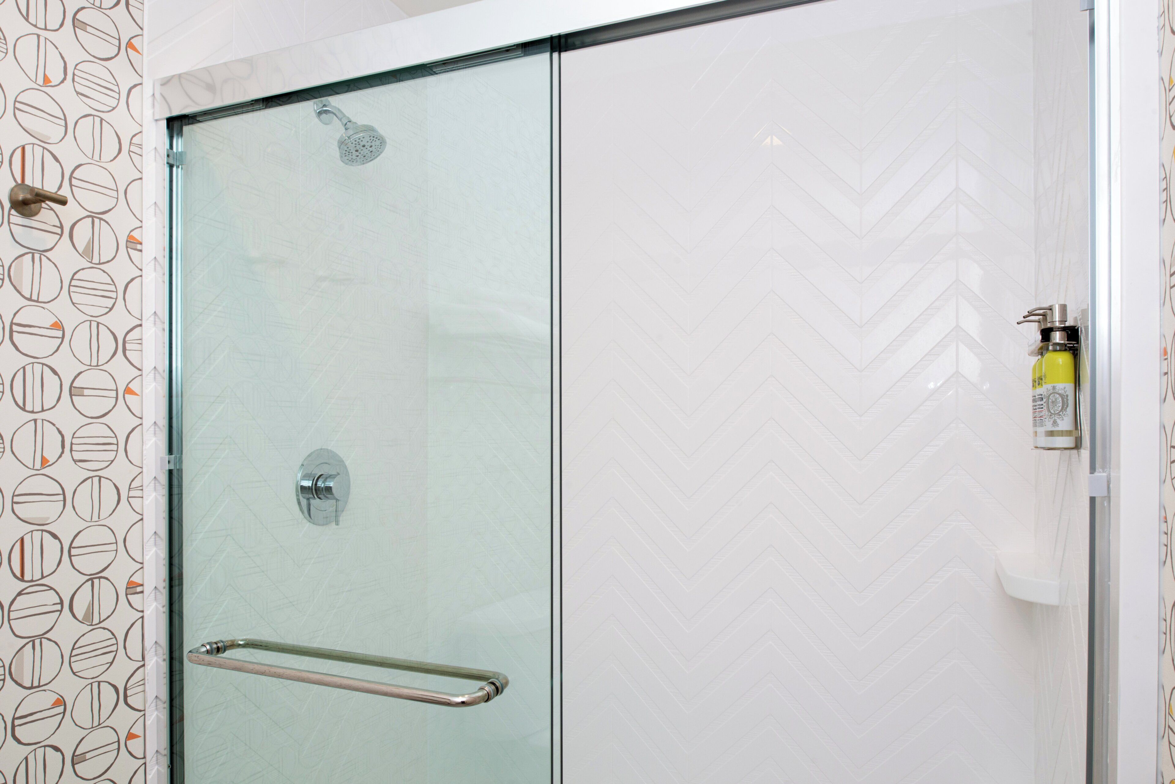 A glass-enclosed shower with a chrome handle and a towel rack on the wall.