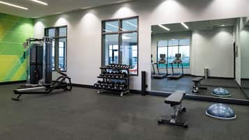 Ett gym med konditionsmaskiner, träningsbänkar och hantlar.