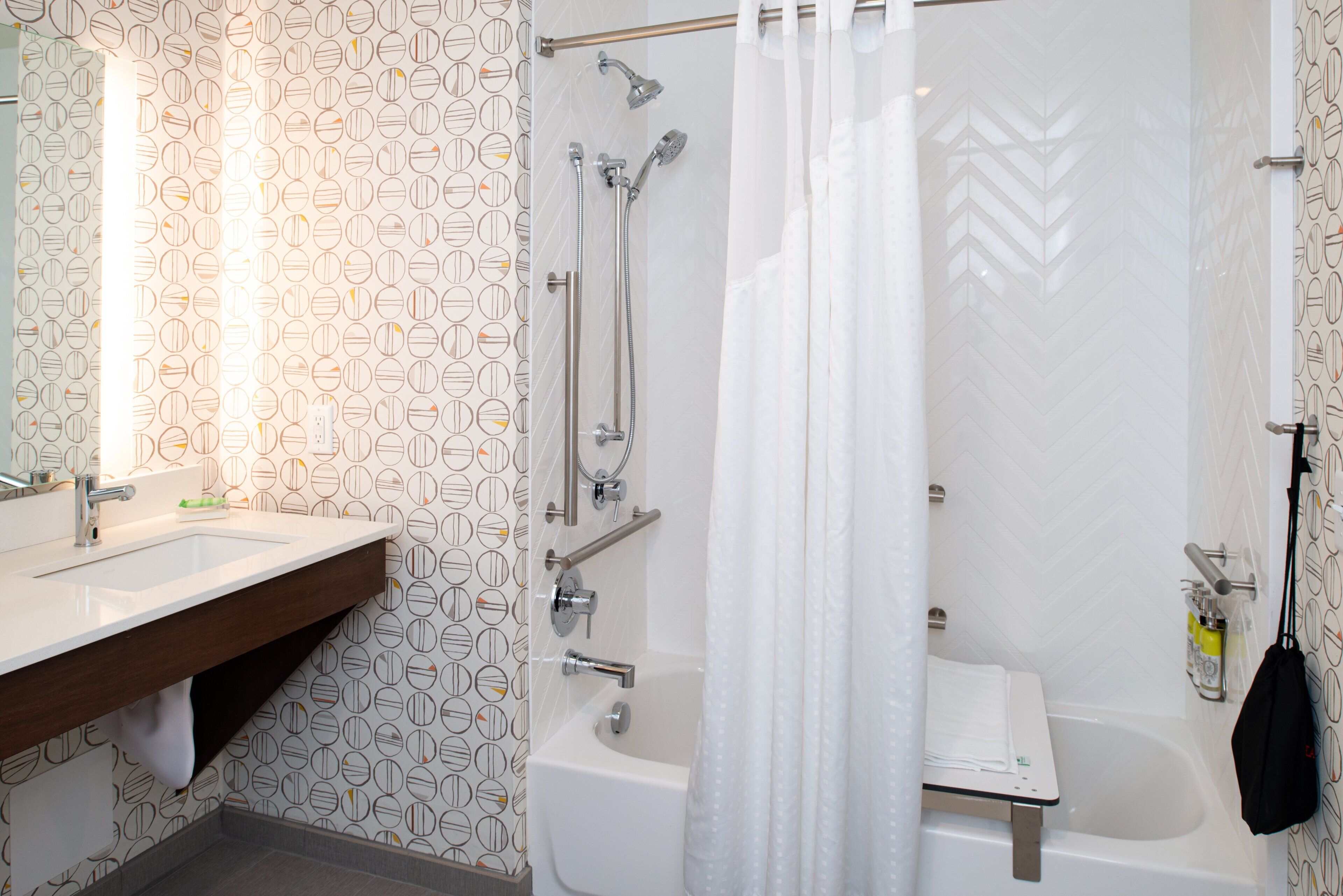 Un baño con lavamanos blanco, espejo y zona de ducha con cortina.