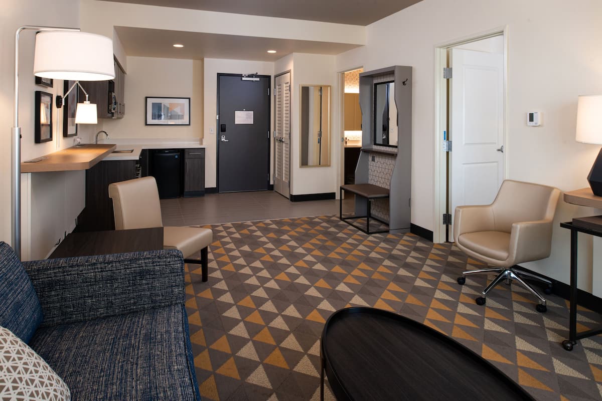 Une chambre d’hôtel avec un canapé, un bureau, une chaise et un sol à motifs.