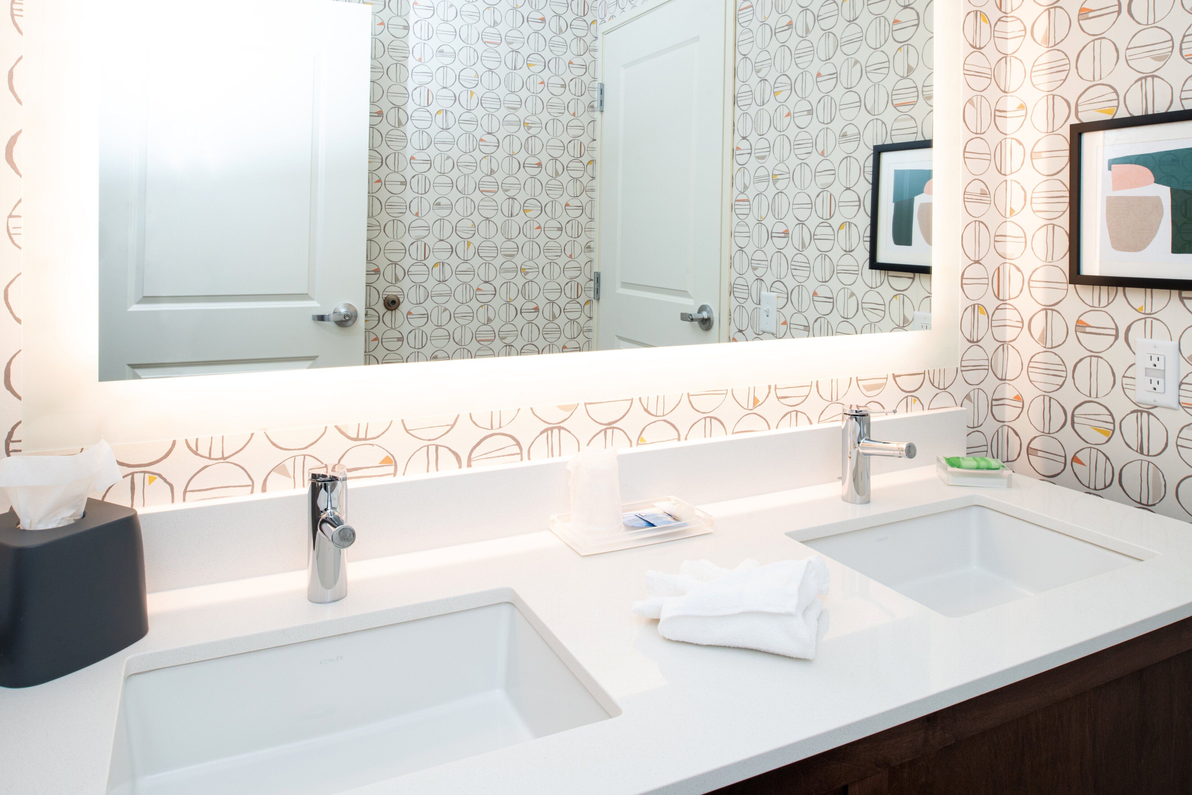 A bathroom with two sinks, a mirror, and a towel rack.