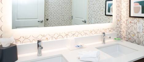 A bathroom with two sinks, a mirror, and a towel rack.