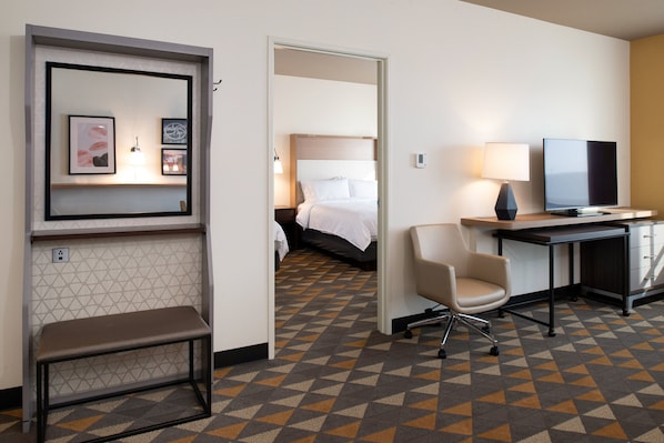 Habitación de hotel con cama, escritorio, silla y un banco.