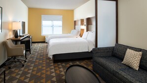 Een hotelkamer met twee bedden, een bank, een bureau en een stoel.