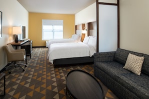 Habitación de hotel con dos camas, un sofá, un escritorio y una silla.