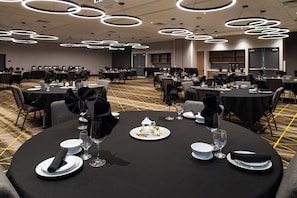 A banquet hall with round tables set for dining, featuring black tablecloths and white plates. - Holiday Inn & Suites Idaho Falls by IHG (Idaho Falls)