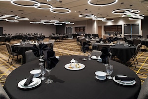 Un salón de banquetes con mesas redondas dispuestas para comer, con manteles negros y platos blancos.