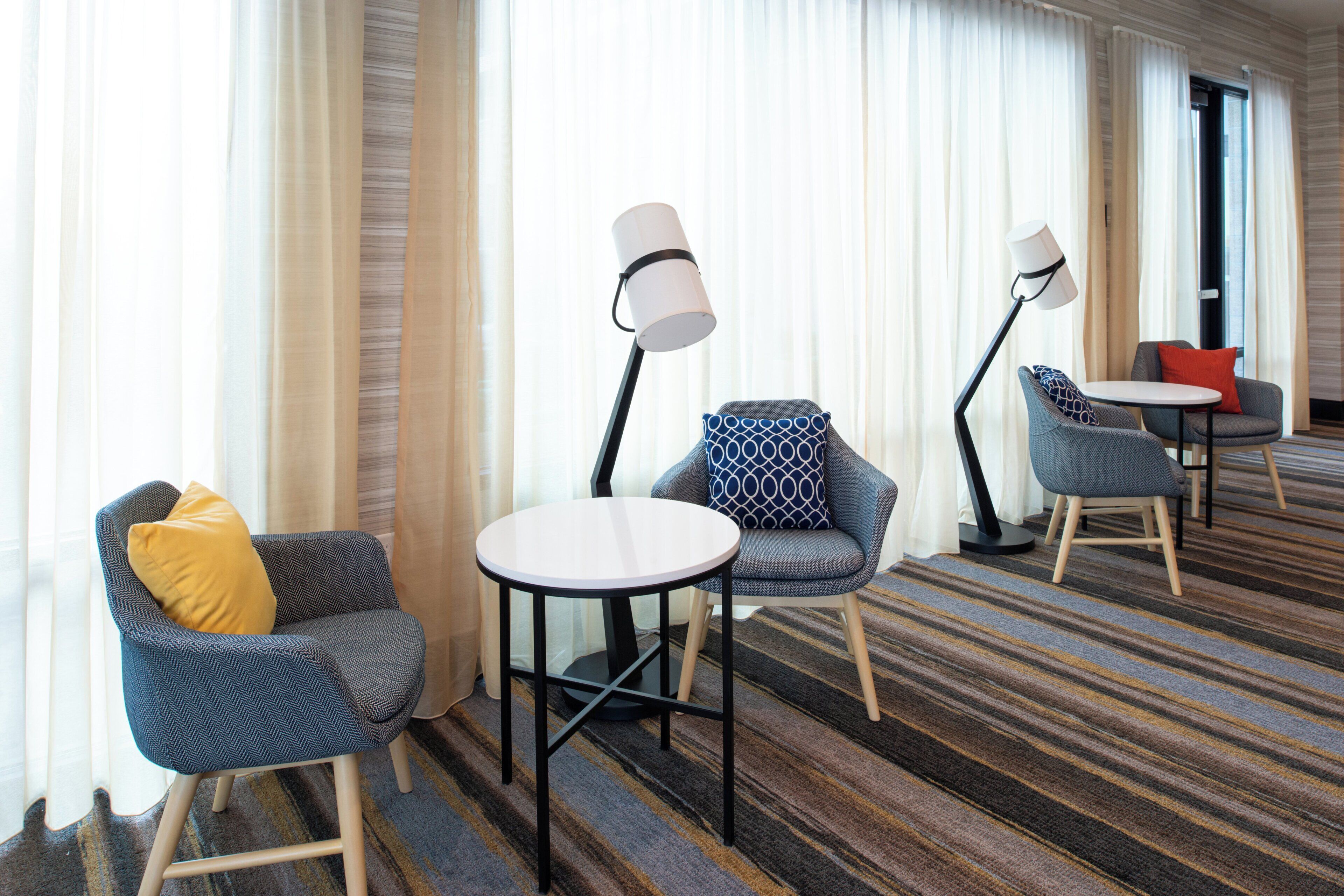 Habitación de hotel con zona de estar que incluye dos sillones, una mesita redonda y dos lámparas de pie.