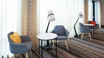 Habitación de hotel con zona de estar que incluye dos sillones, una mesita redonda y dos lámparas de pie.