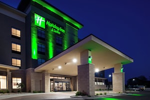 Un hotel Holiday Inn con fachada moderna, señalización iluminada y zona de acceso cubierta.