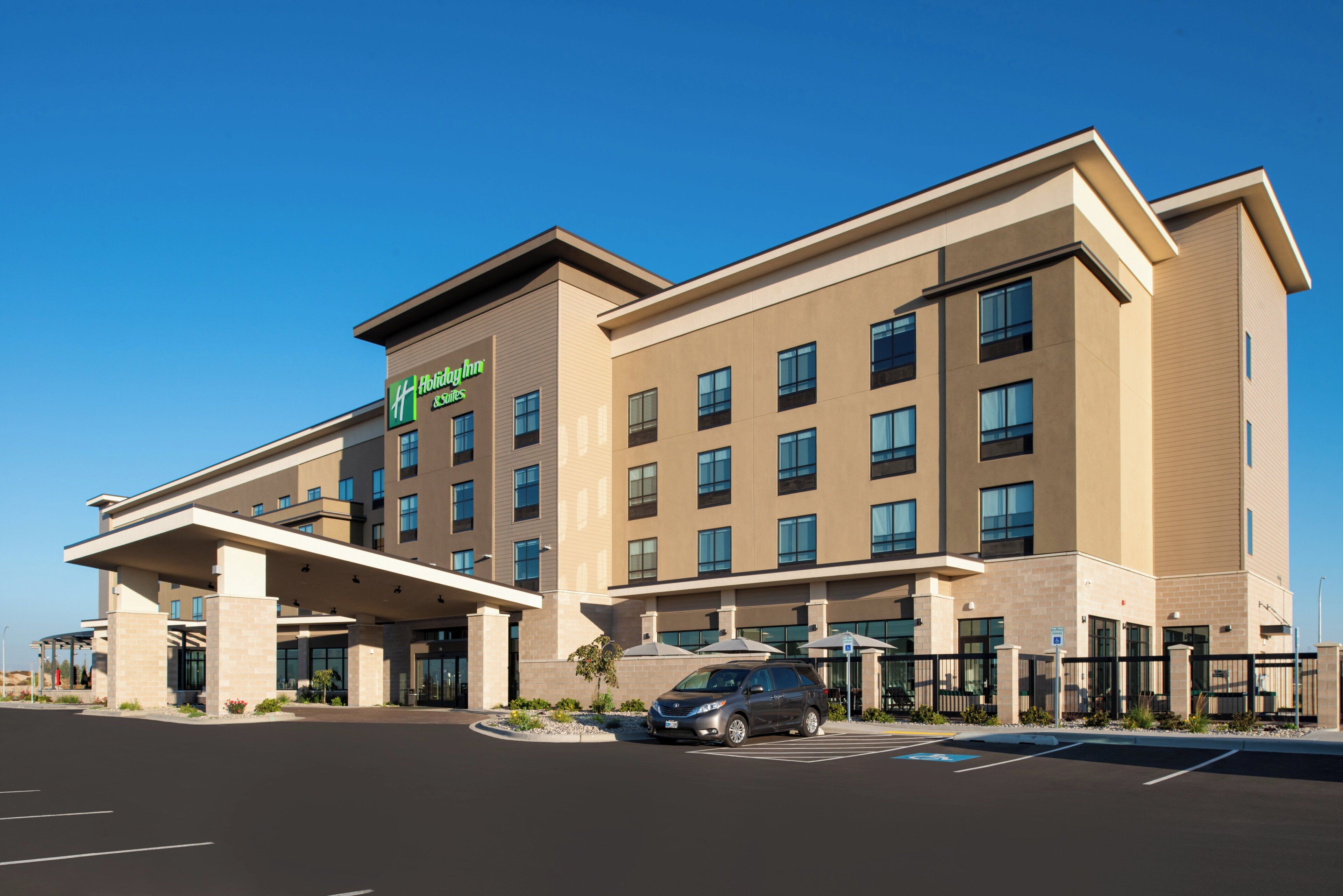 Ein Hotel Holiday Inn Express mit modernem Design, das einen überdachten Eingang und viele Fenster bietet.