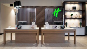 Een receptiebalie met een groot groen 'H'-bord, een computer en een etalage met diverse artikelen.