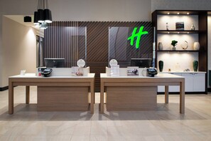 A reception desk with a large green 'H' sign, a computer, and a display of various items.