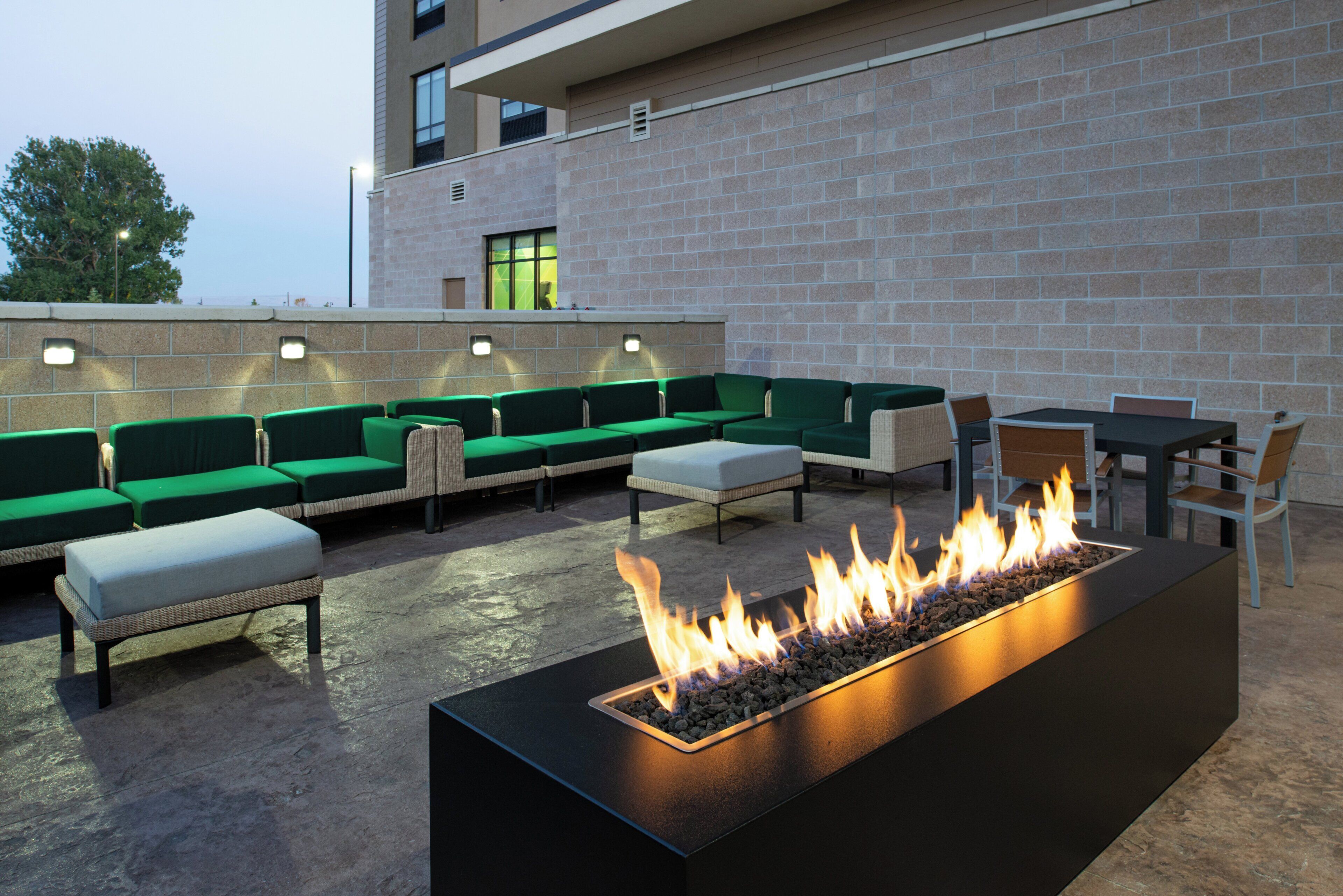 An outdoor seating area with green sofas and a fire feature.