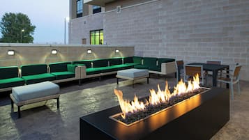 An outdoor seating area with green sofas and a fire feature.