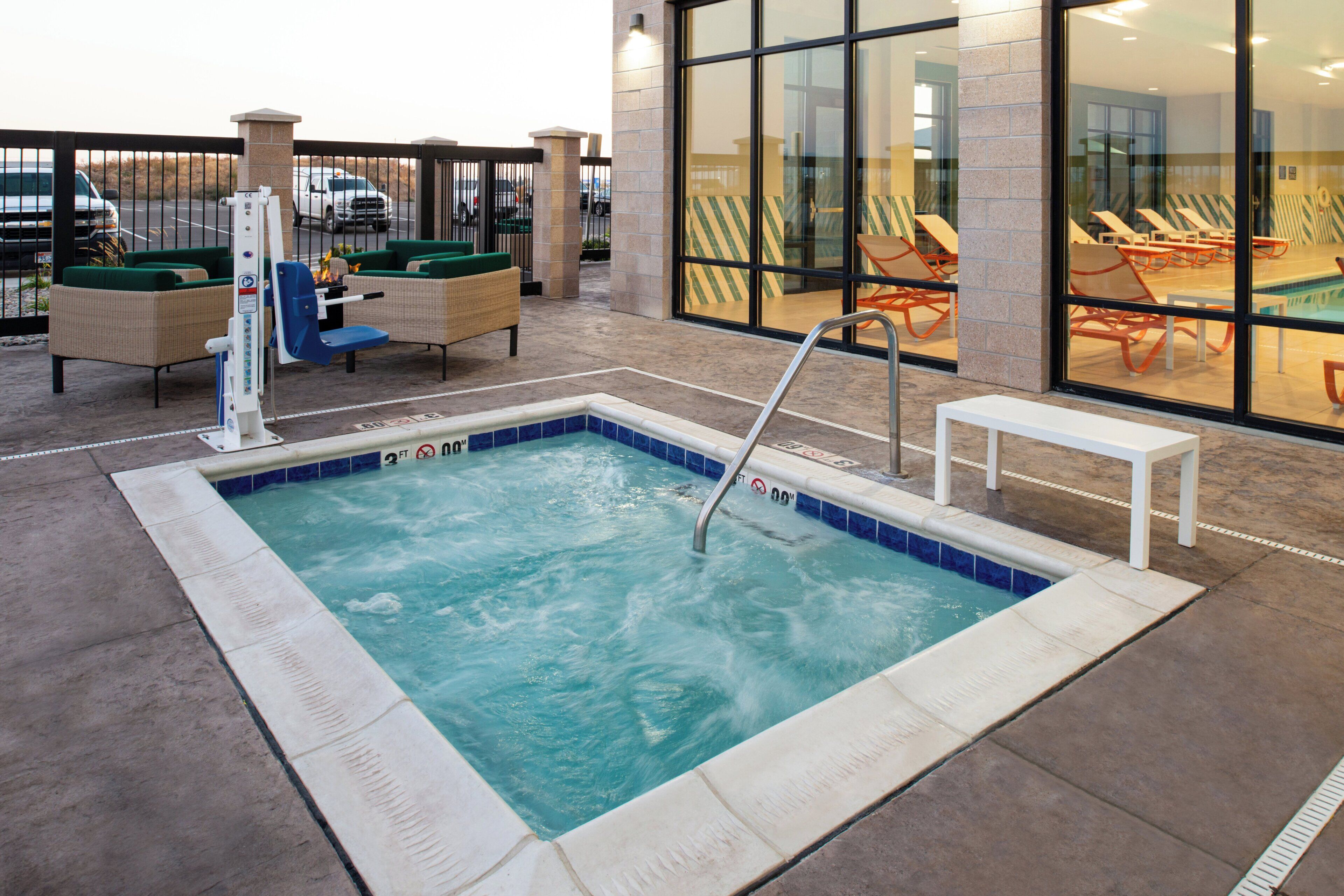 A hot tub area with a pool, lounge chairs, and a glass-enclosed room with additional seating.
