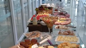 En buffet med forskellige spiser, heriblandt brød, kager og frugt.