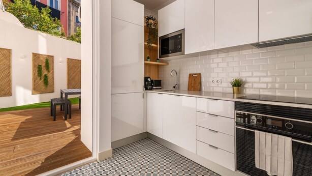 Una cocina moderna con armarios blancos, una estufa negra y un salpicadero de azulejos.