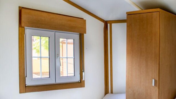 Un dormitorio con una cama individual, un armario de madera y una ventana con vistas al exterior.