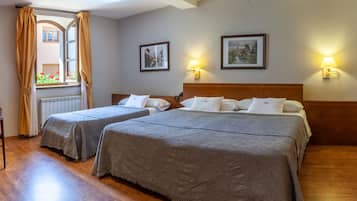 A hotel room with two beds, a wooden desk, a chair, and a window with curtains.
