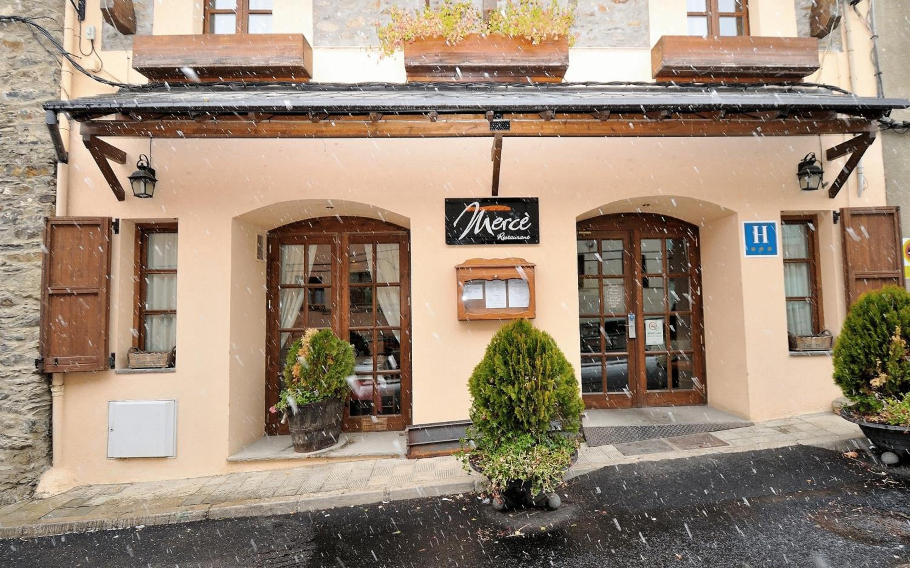 En bygning med et skilt, der viser 'Mercé Restaurant', og et symbol for handicapvenlig adgang.