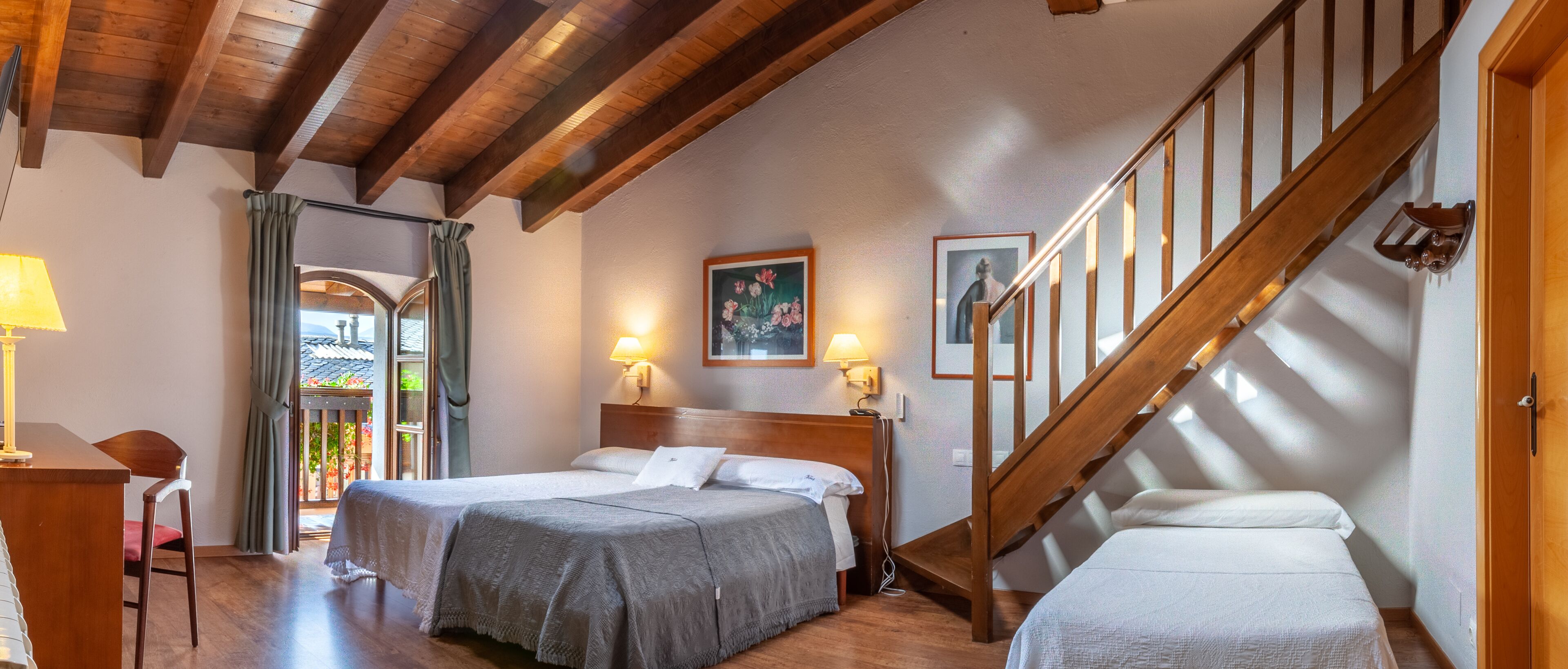 Un dormitorio con dos camas, vigas de madera, una escalera y vistas a un jardín.