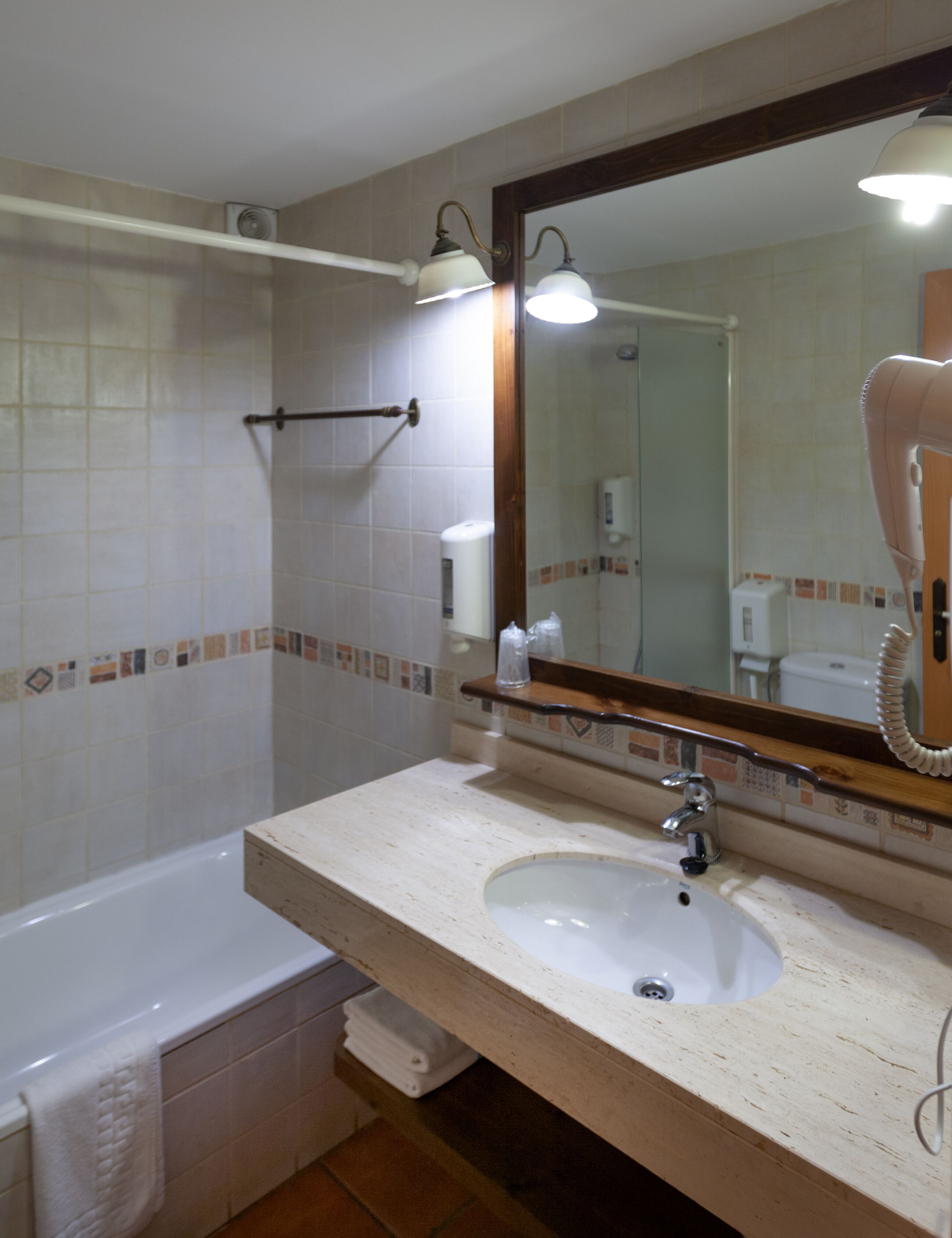 A bathroom with a bathtub, a sink, a mirror, and a hairdryer.