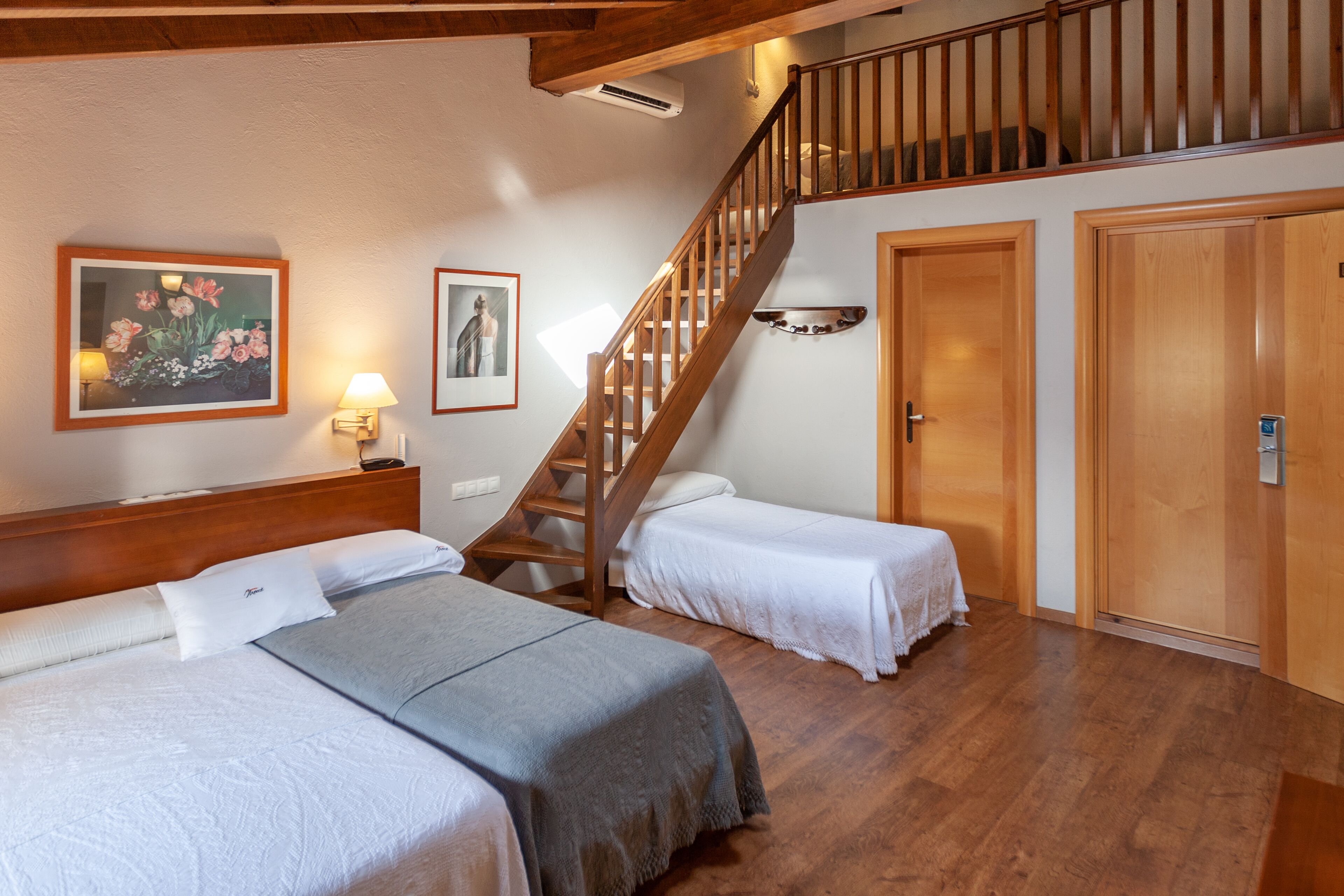 Ein Hotelzimmer mit zwei Betten, einer Holztreppe und einer Tür.
