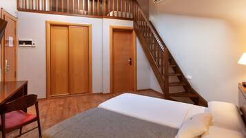 Un dormitorio con cama, escritorio, silla y escalera.
