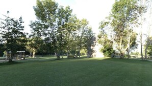 Un parque con césped verde, árboles y un pequeño pabellón.