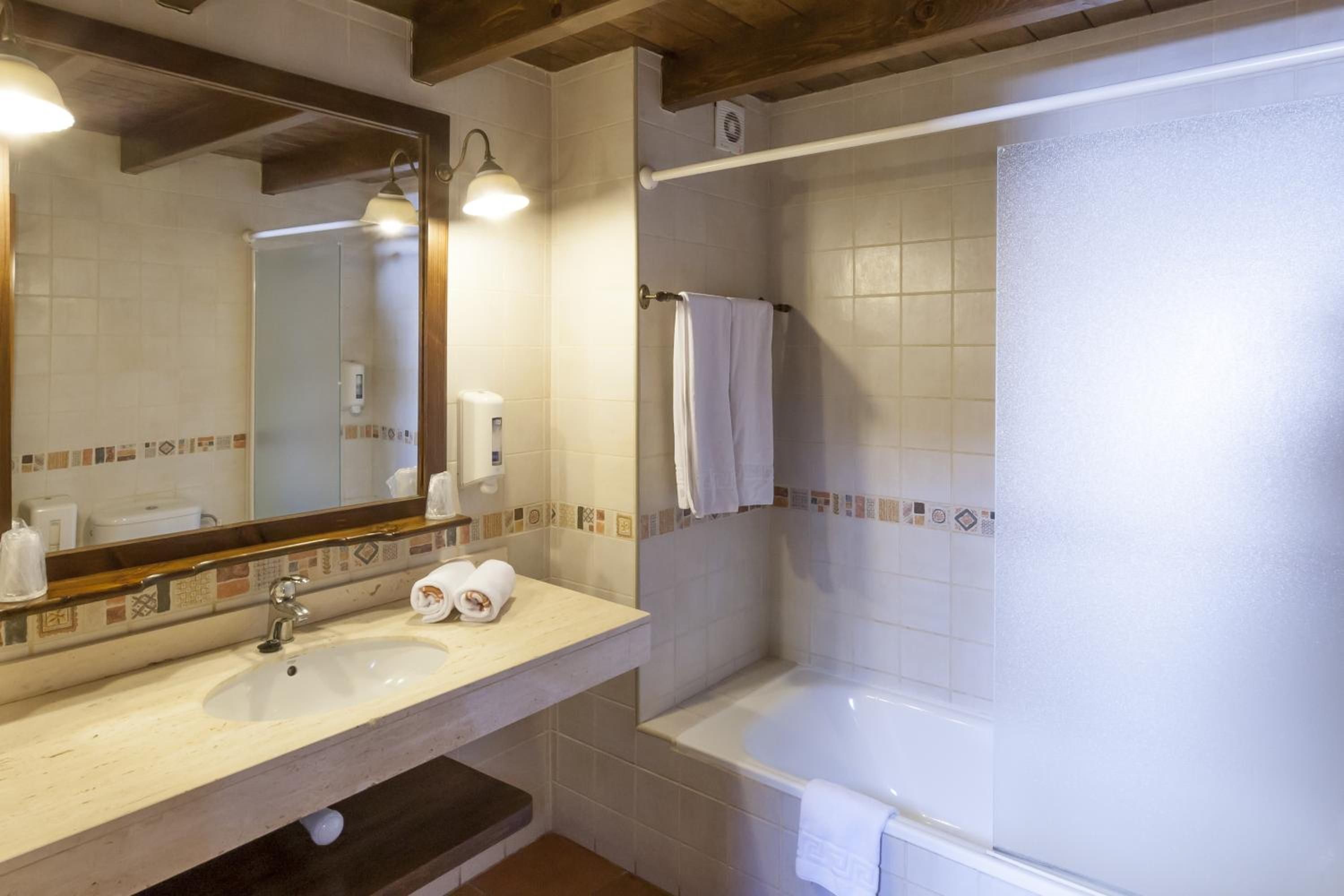 A bathroom with a sink, mirror, towel rack, and bathtub.