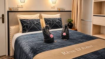 A hotel room with a bed, two wall-mounted light fixtures, a bedside table with a plant, and a wardrobe.