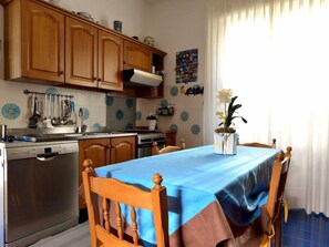 Una cocina con armarios de madera, estufa de acero inoxidable y una mesa de comedor con mantel azul.