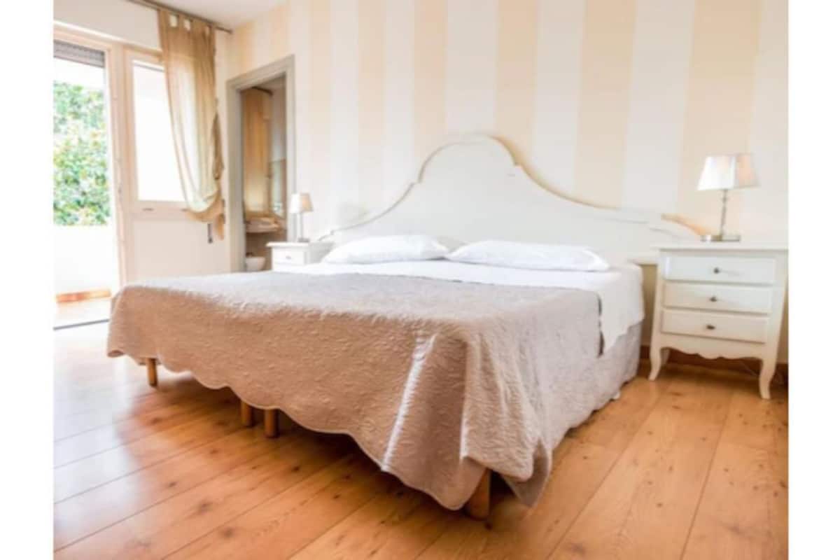 A bedroom with a bed, bedside tables, and a window.