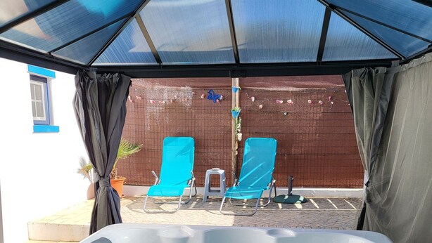Een bubbelbad met twee blauwe ligstoelen onder een blauw dakzeil.