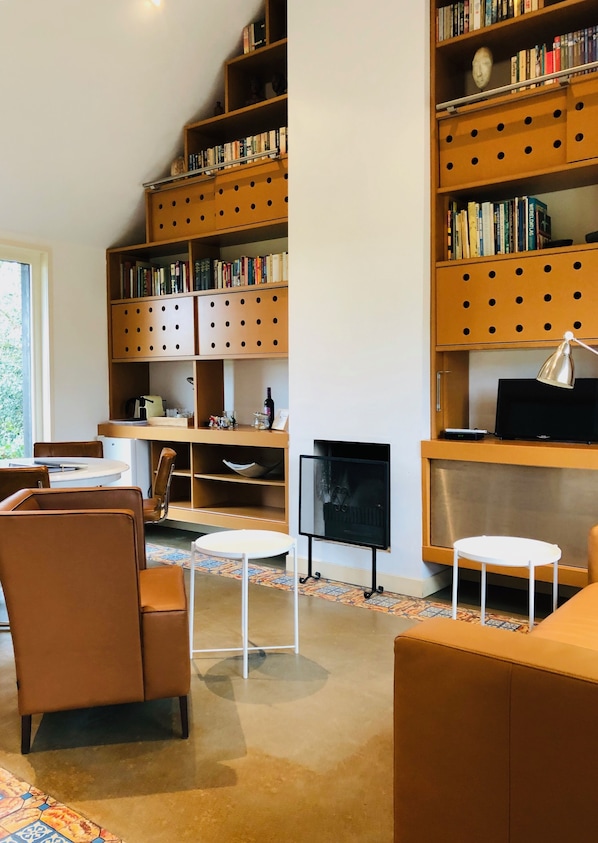 A modern living room with a fireplace, bookshelves, a television, and comfortable seating. - Hof van Eersel (Eersel)