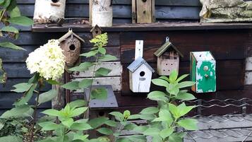Un conjunto de casas para pájaros frente a una pared de madera, rodeado de follaje.