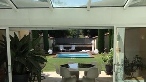 A modern indoor space with a glass ceiling, a pool, and a dining area with chairs and a table. - Au 120 (Albi)