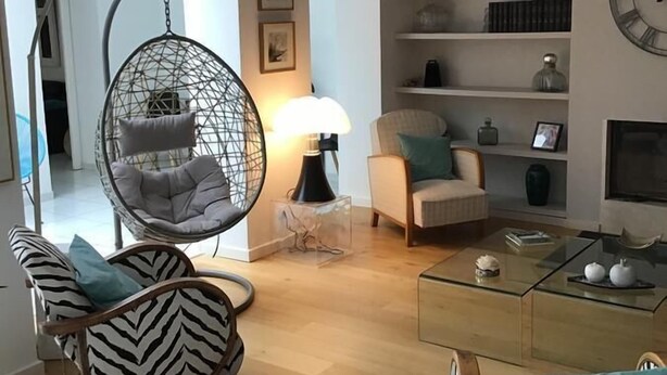 A modern living room with a hanging chair, a sofa, a glass coffee table, and a fireplace. - Au 120 (Albi)