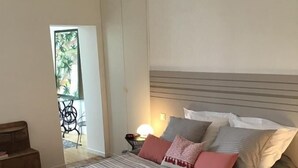 A bedroom with a bed, wooden floor, nightstand, and a view of a balcony. - Au 120 (Albi)